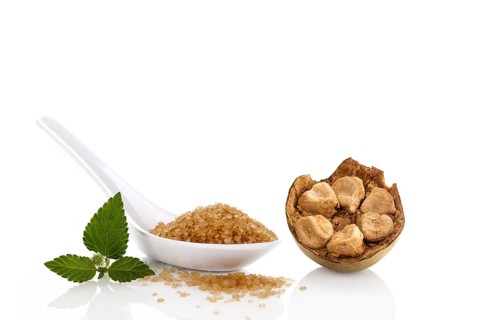 Heap of brown cane crystallized sugar in white spoon and monk fruit, luo han guo isolated on white
