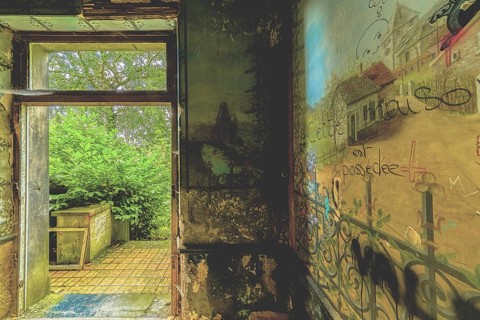An abandoned room with dilapidated walls and an open door leading to nature, Château d'Ah, Lost