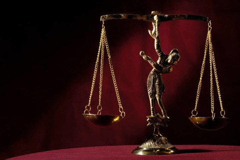 Stock photo of Shiny golden empty balanced vintage justice scales isolated on dark red background