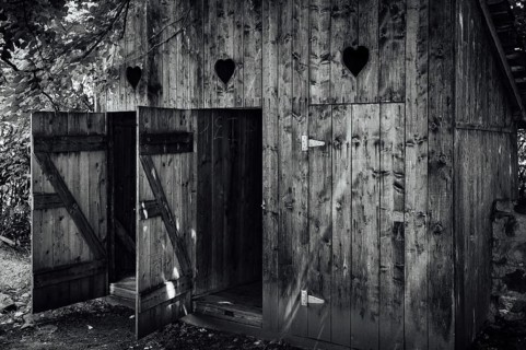 Open doors to old wooden outhouses. Romania