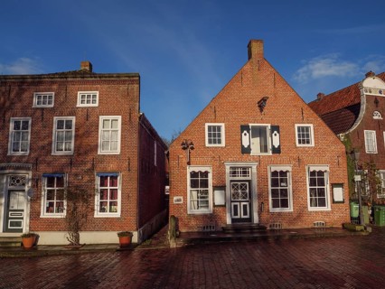 Two brick houses with beautiful façade and balcony under a blue sky, Greetsiel, East Frisia,