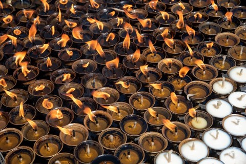 Group of oil religious candles glowing with orange flames on a hindu temple. Symbols of faith and