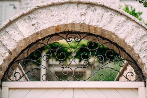 Arched metal forged lattice in a stone fence. Close-up.