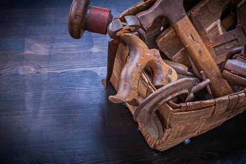 Set of vintage tools in wicker box on wooden board