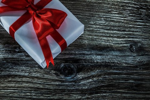 White present box with red bow on wooden board