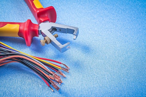 Insulated wire strippers electric cables on blue background electricity concept