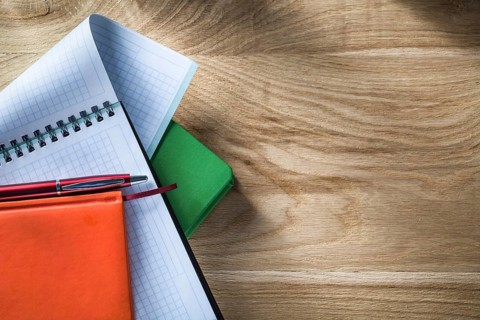 Spiral checked copybook notepads biro pen on wooden board
