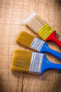 Three paint brushes on wooden board construction concept