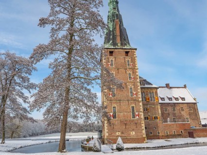 A castle with high towers, snow-covered trees and a clear sky in winter, raesfeld, münsterland,