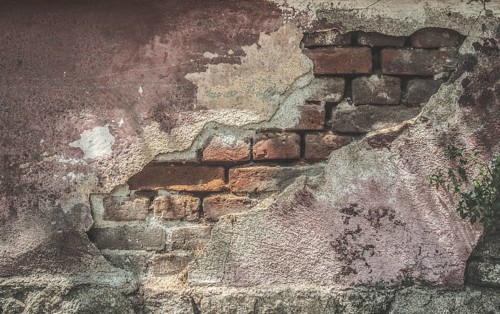 Broken plaster and brick wall. Sunlight