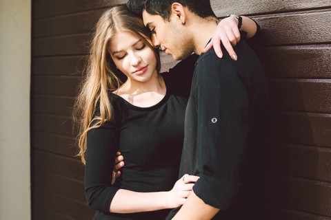 Portrait of attractive Mixed-race couple standing together against the background of a wooden wall.