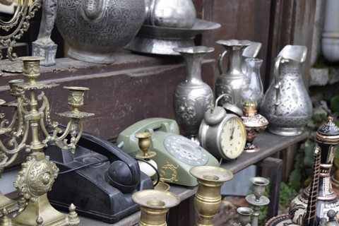A vintage display of metallic jugs, candelabras, old phones, and a clock, Turkey