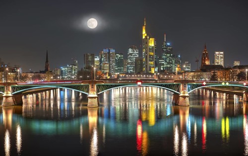 The illuminated skyline of the city centre of Frankfurt am Main at night and full moon with the