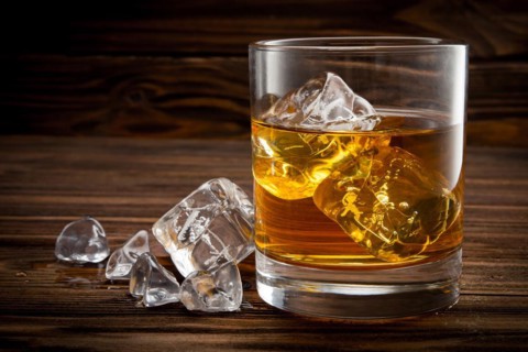 Closeup of glass with ice and whiskey on wooden background