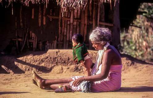 A jenu kurumba tribal old woman with her grandson. Baby urinating in Nagarahole tribal settlement