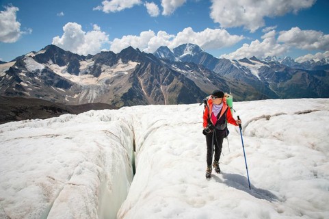 Female mountaineer enjoying the beauty of the glacier walks on the glacier in the crampon and