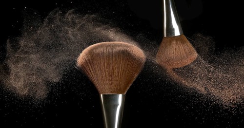 Make-up Brush spreading blush powder on black background