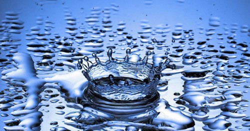 Drop of Water falling into Water against Blue background