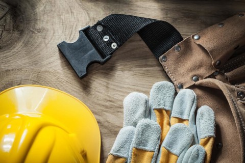 Leather belt Safety gloves Safety helmet on wooden board