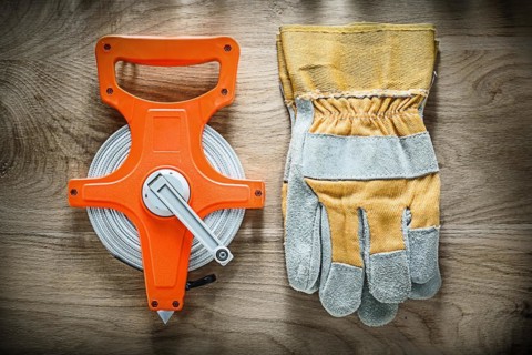 Pair of safety gloves Tape measure on wooden board