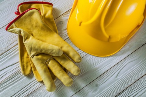 Yellow leather work gloves and construction helmet on old white lacquered wooden panels