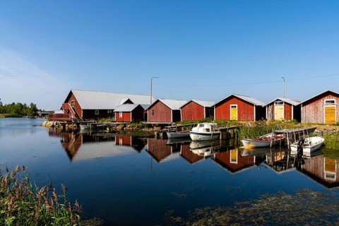 Svedjehamm, Finland - 28 July, 2021: colorful fishing cottages and boats reflected in the water