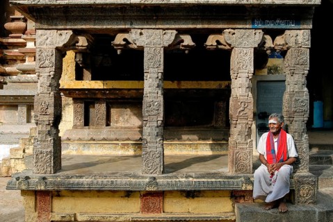 Old man sitting in front of Kandarathithan Gopuram in Virudhagireeswarar Shiva temple in