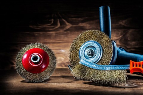 Angle grinder with wire grinding discs and hand wire brush on old wood