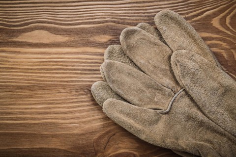 Brown protective gloves on vintage wooden board Construction concept