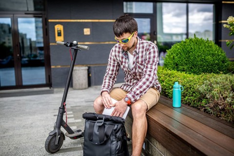 Handsome hipster style bearded man works online freelancer, pulls out laptop with backpack and
