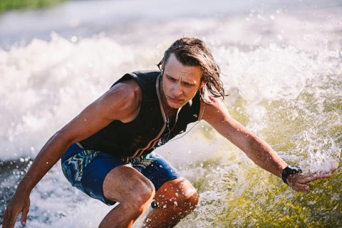 Active wakesurfer jumping on wake board down the river waves. Surfer on wave. Male athlete training