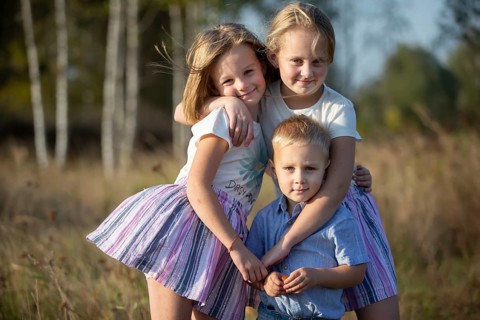 Little brother and two sisters are looking at the camera