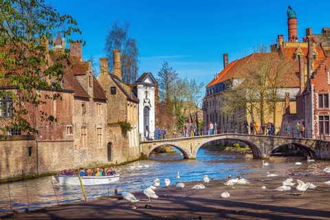 Bruges, Belgium, April 10, 2016: Canal and bridge view with tourists in popular belgian