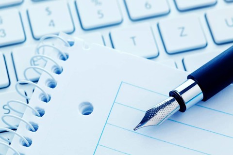 A notepad and the keyboard of a computer. Take notes and save them. Austria