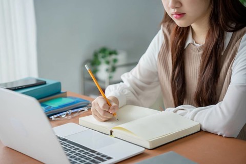 Asian woman using laptop to study student engaged in online learning at college