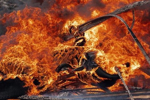 Burning cars wheels, strong flame of red-orange fire and clouds of black fumes. Selective focus,