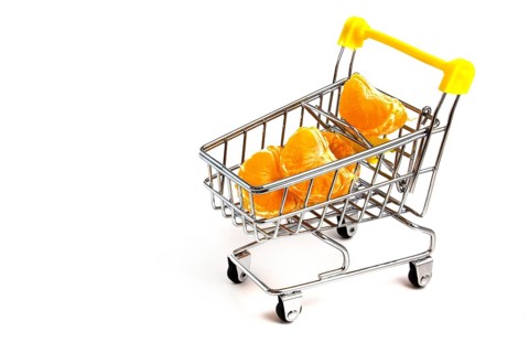 Particles of peeled tangerine in a shopping cart isolated on white background