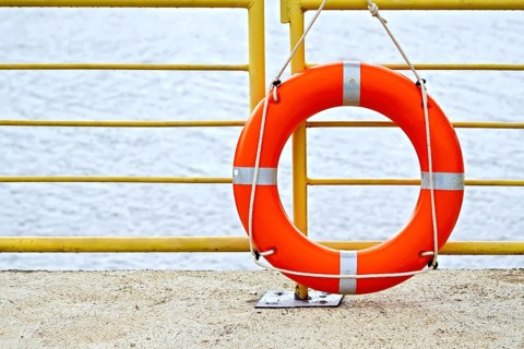 Lifebuoys red hanging on the yellow fence on the background of water