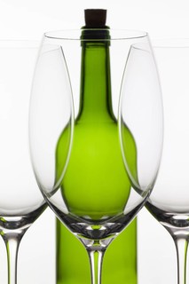 Three empty glasses of wine and green bottle on the white background