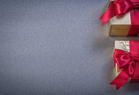 Boxed wrapped presents with red tapes on grey background copy space holidays concept