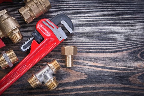 Set of monkey wrench brass connectors on wooden board plumbing concept