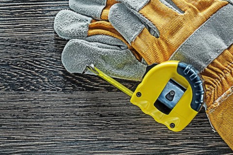 Tape measure pair of protective gloves on wooden board