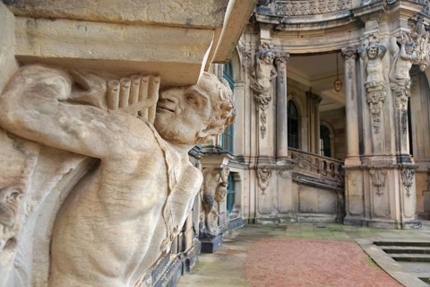 Closeup half naked faunus statue under column with panpipe at Zwinger palace in Dresden, Germany
