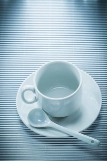 White ceramic cup saucer teaspoon on striped background