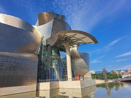 Futuristic building with curved metal shapes under a blue sky reflects innovative architecture,