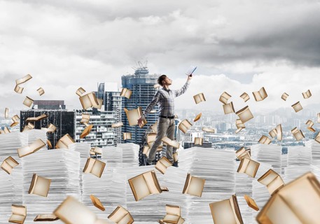Man in casual wear keeping hand with book up while standing among flying books with cityscape on