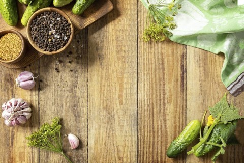 Wooden background with cucumbers prepared for pickling and ingredients for the marinade. Canned