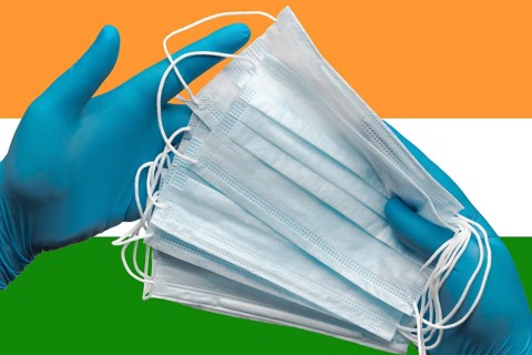 Doctor holding face masks in hands medical blue gloves on background national flag of India.