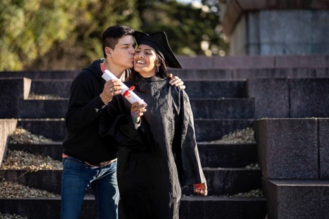 Transgender woman recent graduated, dressed in cap and gown, showing off his degree celebrating