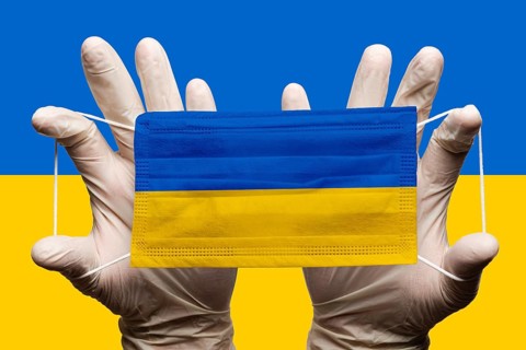 Doctor holding in white gloves protection medical face mask with National flag of Ukraine